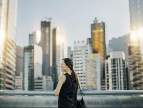 Beautiful young Asian woman enjoying the city view during sunset on urban balcony